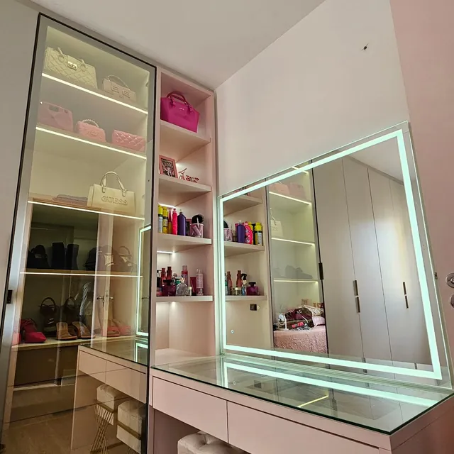 Closet com penteadeira, espelho iluminado e armário com portas de vidro