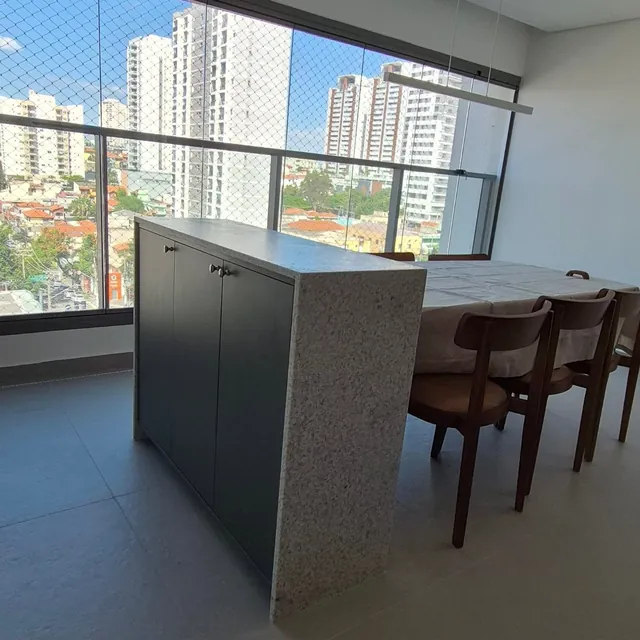 Ilha verde-escura com tampo de granito em varanda envidraçada