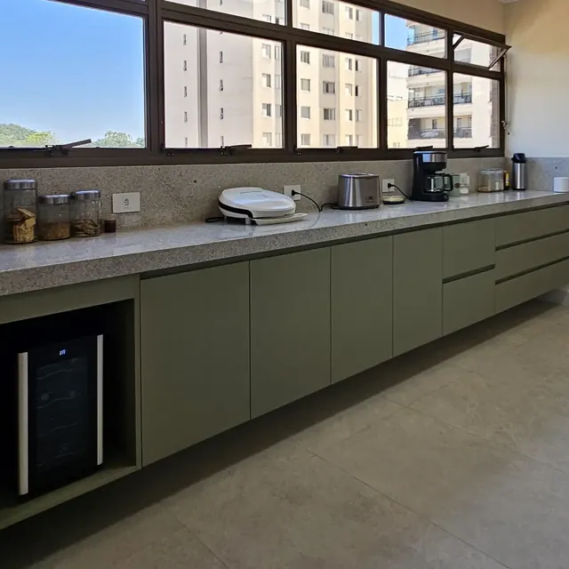 Cozinha planejada com armários verde-sálvia sob bancada de granito