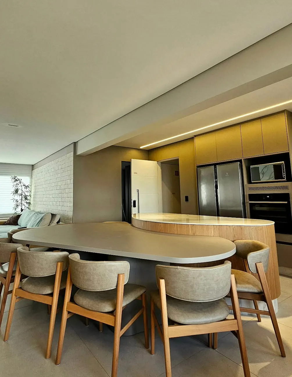 Mesa de jantar curva sob medida integrada à ilha da cozinha, com cadeiras de madeira