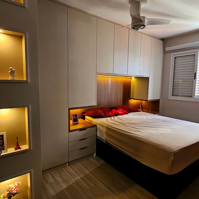 Quarto de casal com guarda-roupa até o teto, cabeceira em madeira e nichos iluminados