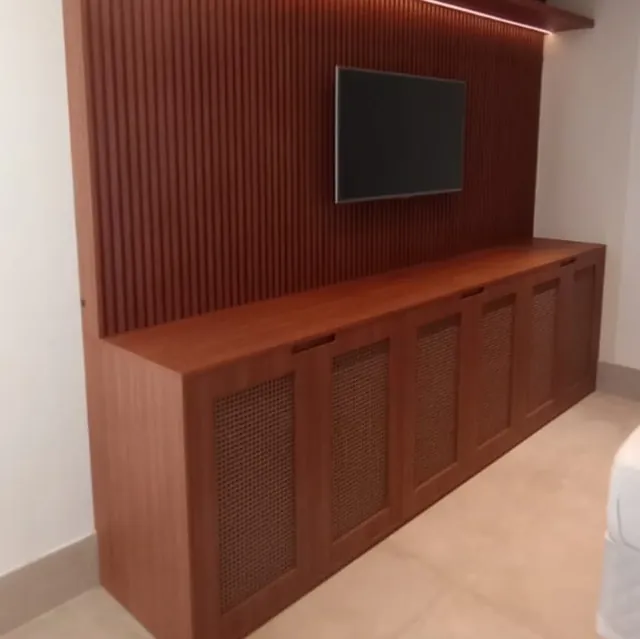Painel ripado de madeira com TV e aparador com portas de palhinha